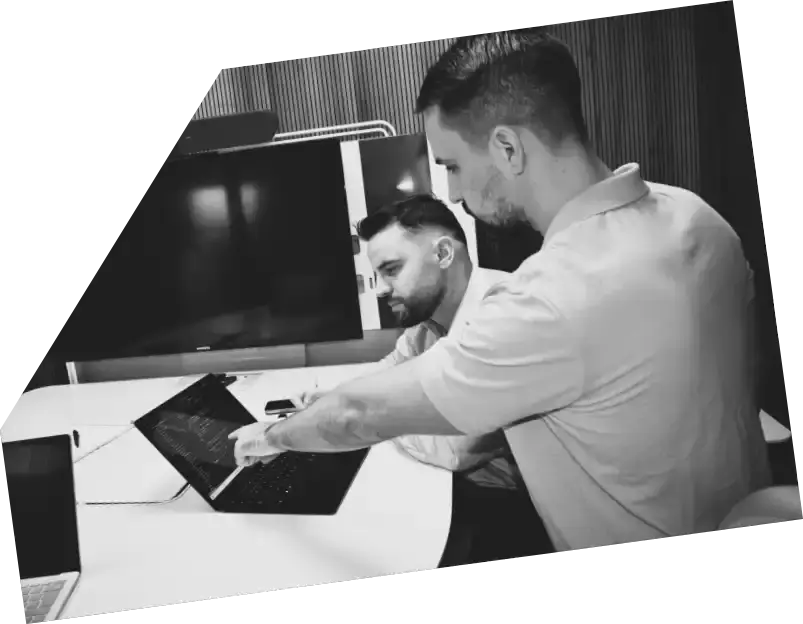 Zwei Personen arbeiten mit einem Laptop in einem modernen Büro.