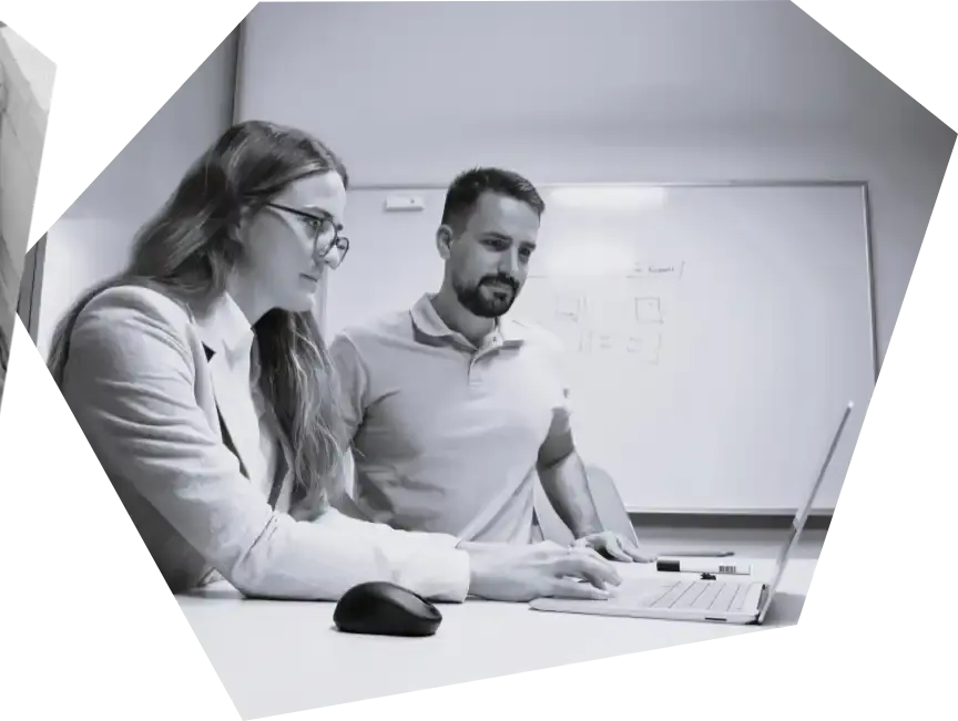 Zwei Personen arbeiten zusammen an einem Schreibtisch Whiteboard im Hintergrund.